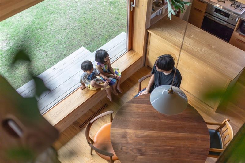大開口サッシを開けて自然素材の家で家族団欒をしている写真です。